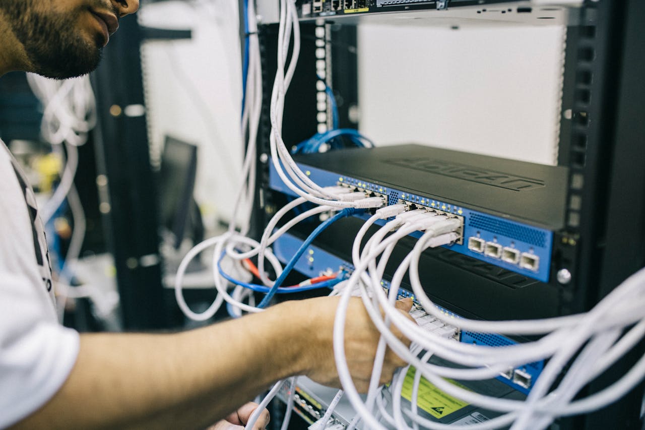 about-02 An IT professional configuring network cables in a server rack, focusing on Ethernet connections.